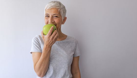 Frau, beißt in einen Apfel.