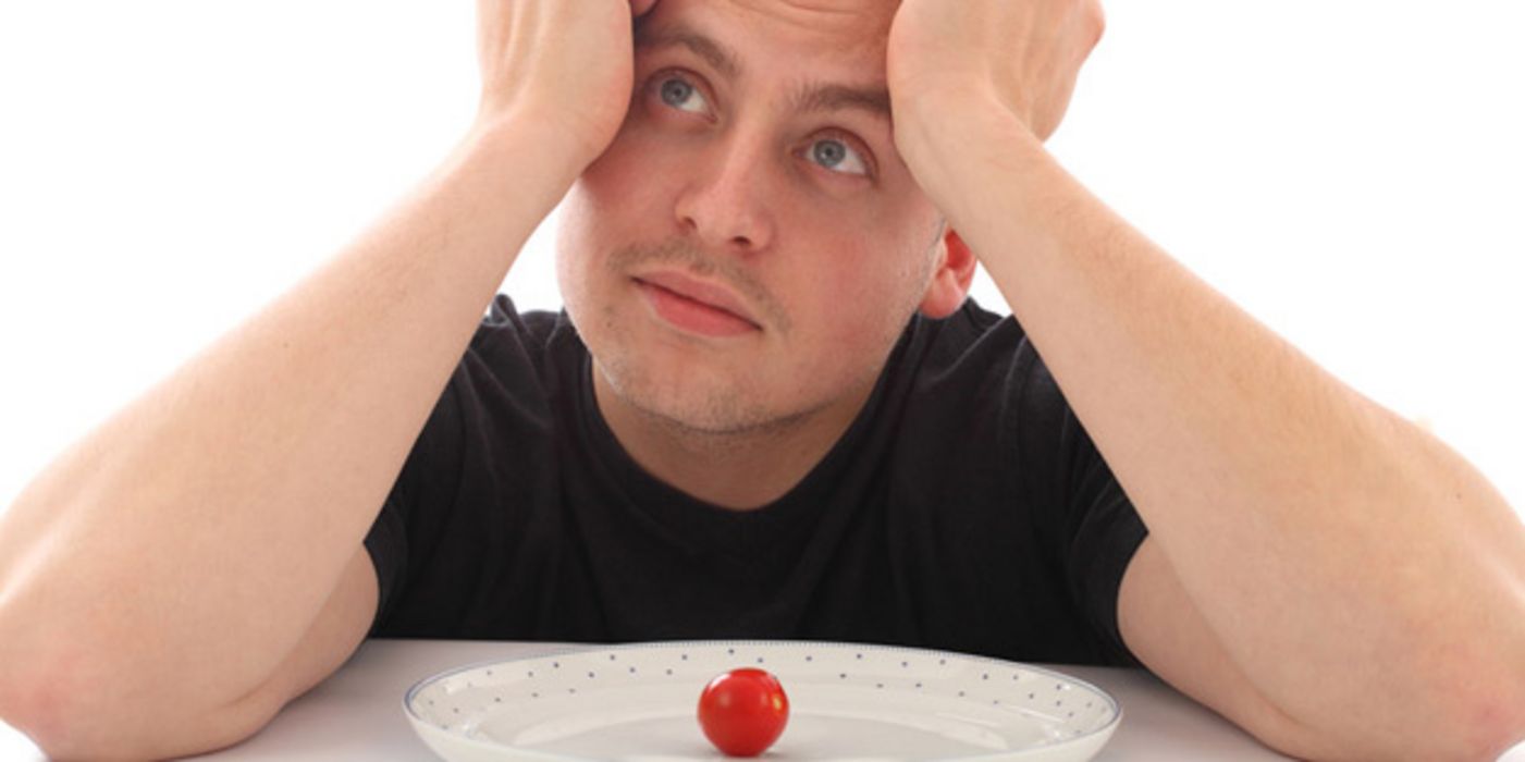 Verzweifelter Mann vor einem Teller mit einer Tomate