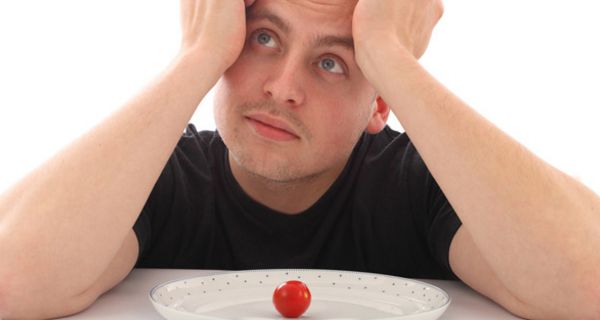 Verzweifelter Mann vor einem Teller mit einer Tomate