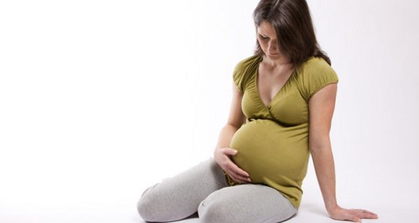 Schwangere Frau hält sich die Hand an den Bauch