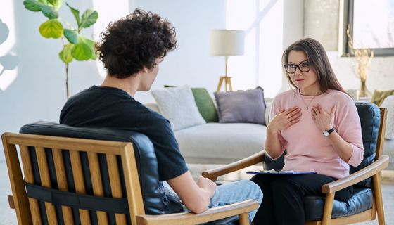 Junger Mann in Psychotherapie-Sitzung mit Therapeutin