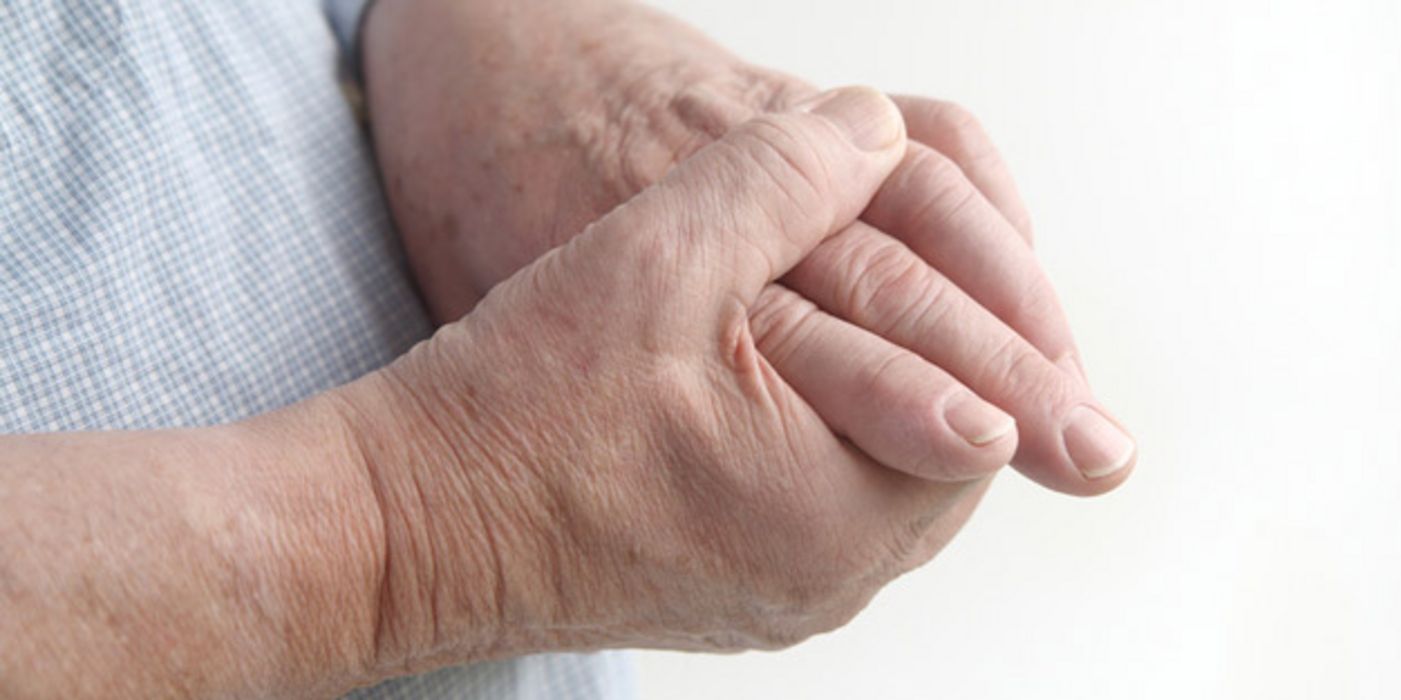Gicht-Patient betastet seine schmerzenden Hände