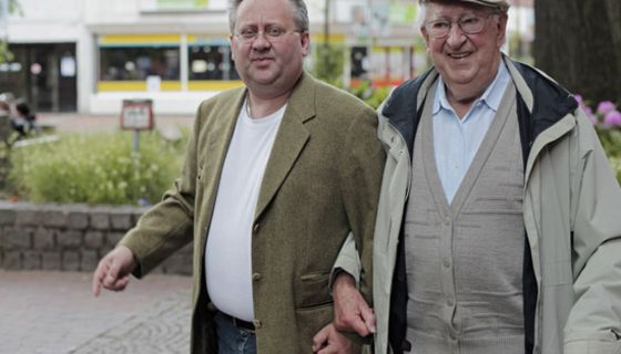 Zwei ältere Herren beim Spazierengehen; einer mit Stock