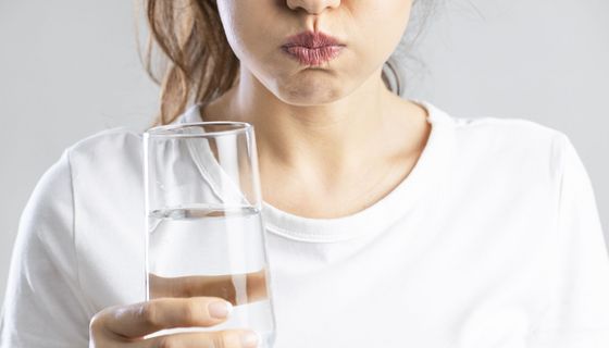 Frau, gurgelt mit Salzwasser.