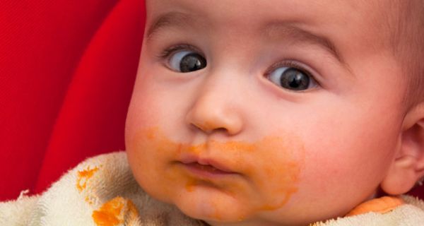 Nahaufnahme eines breiverschmierten Kleinkindergesichts mit erstaunt aufgerissenen Augen