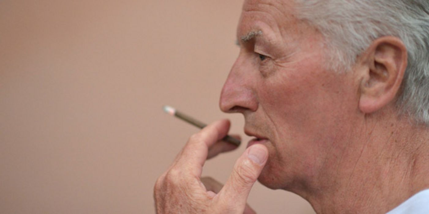 Porträtfoto: Profil Mann um die 70, rechter Bildrand, einen Zigarillo rauchend