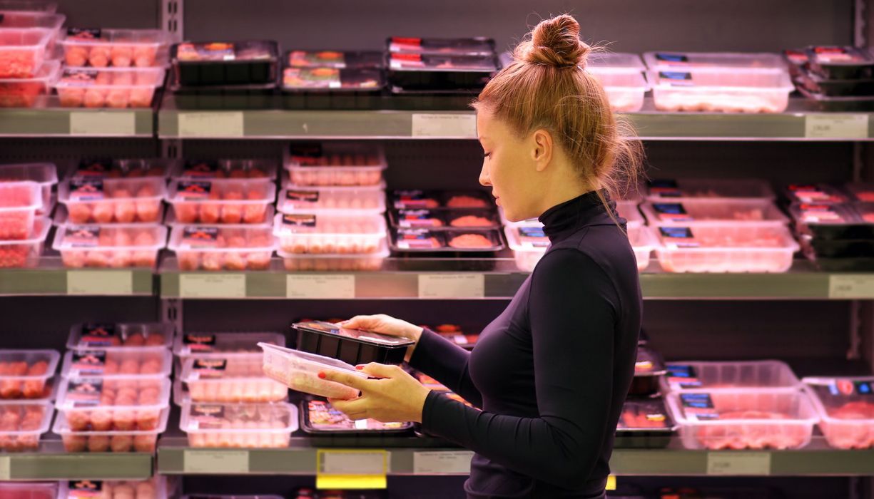 Frau vor der Fleischtheke im Supermarkt.