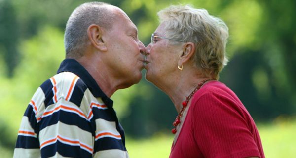 Alter Mann und alte Frau küssen sich.