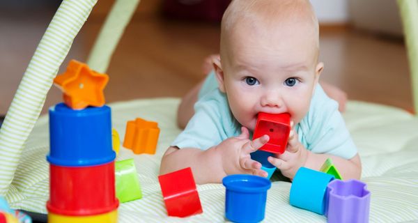 Baby, hat Spielzeug im Mund.