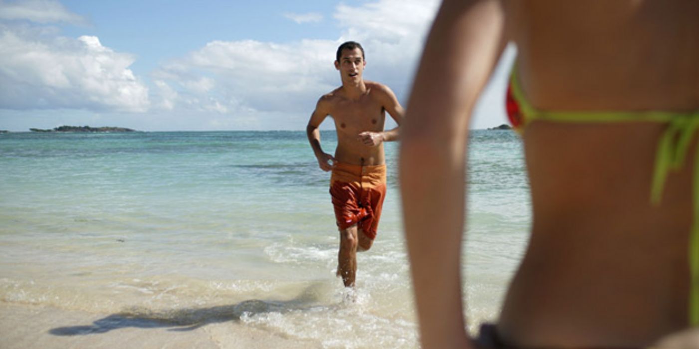 Junger Mann joggt am Strand.