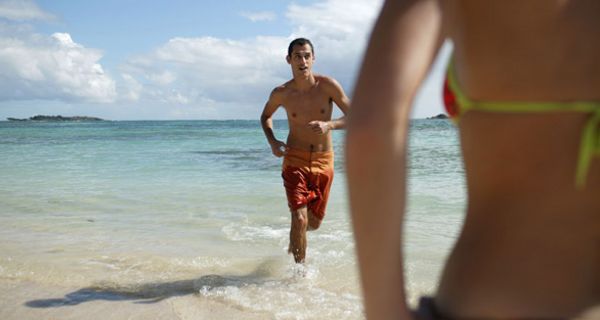 Junger Mann joggt am Strand.