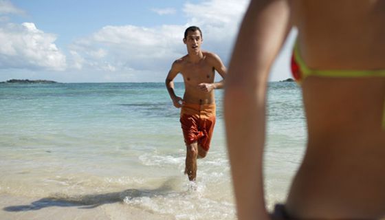 Junger Mann joggt am Strand.