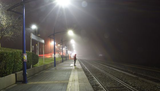 Beleuchtete Bahnhaltestelle mit einer Person