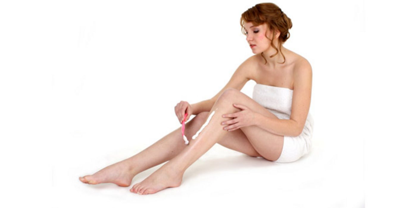 Frau rasiert sich die Beine.
