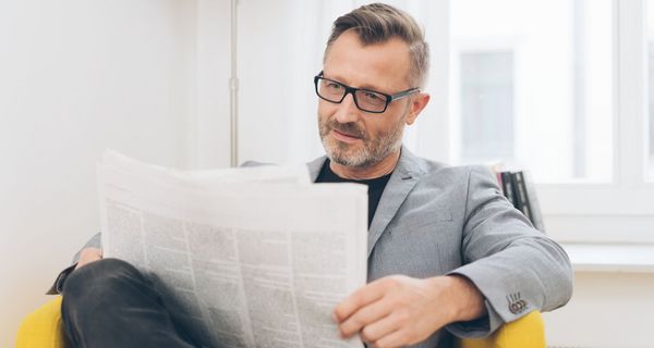 Mann, 50+, mit Brille liest Zeitung.