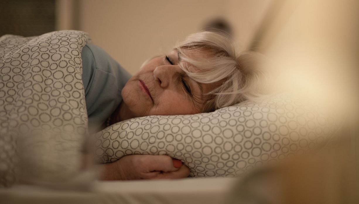 Ältere Frau, liegt im Bett und schläft.