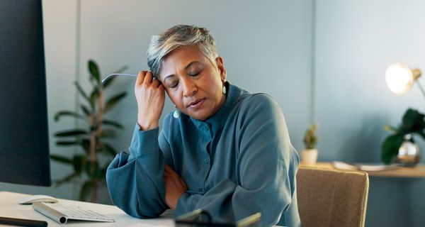 Frau, sitzt müde am Schreibtisch.