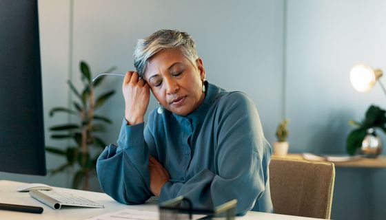 Frau, sitzt müde am Schreibtisch.