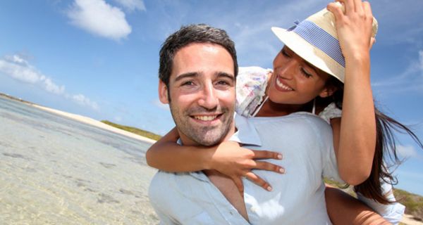 Junges Paar am Strand, er trägt sie huckepack