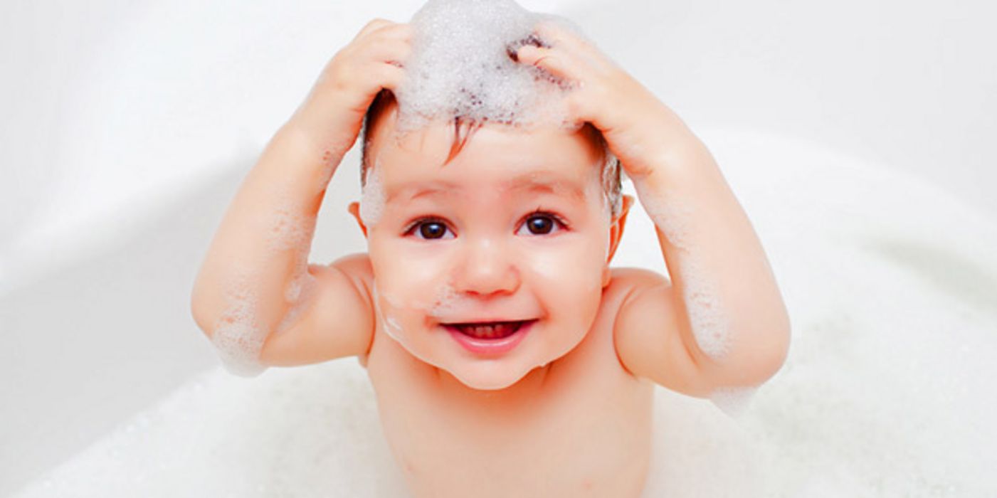 Kleinkind wäscht sich die Haare in der Badewanne.