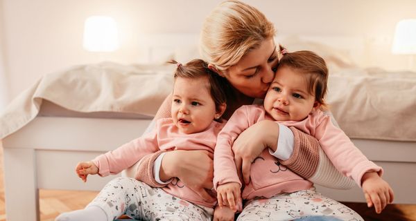 Mutter mit Zwillingsbabys auf ihrem Schoß.