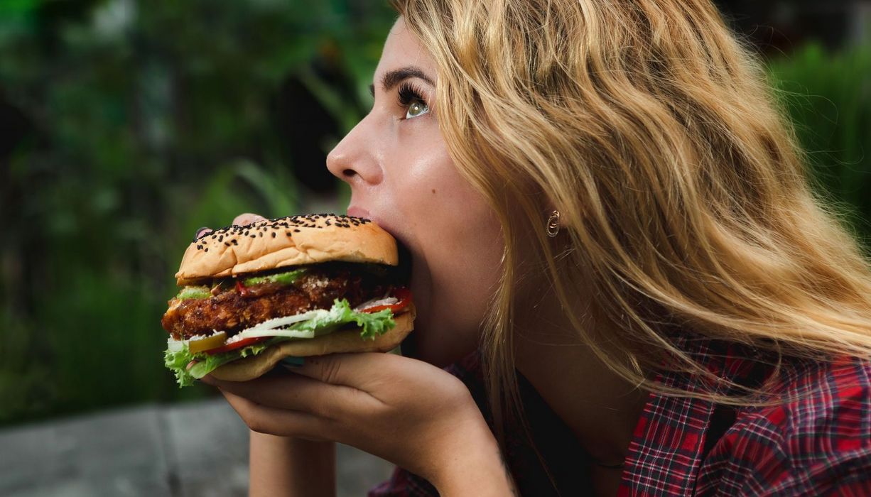 Frau beißt in Hamburger.