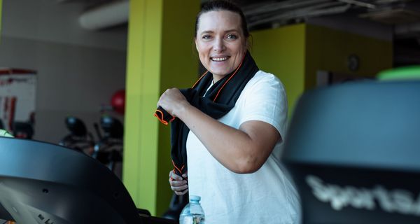 Frau mit leichtem Übergewicht, joggt auf einem Laufband.