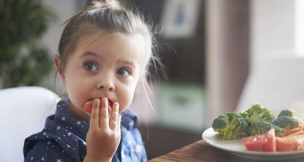 Kleines Mädchen isst Gemüse.