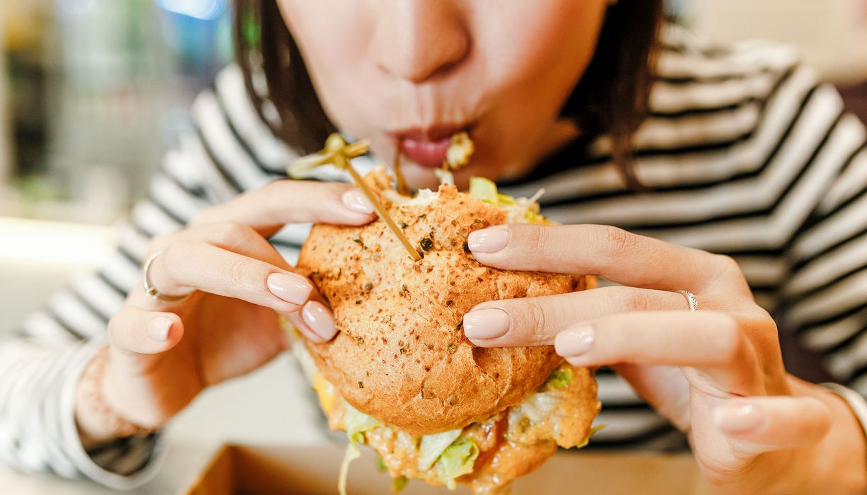 Frau, isst einen Burger. 