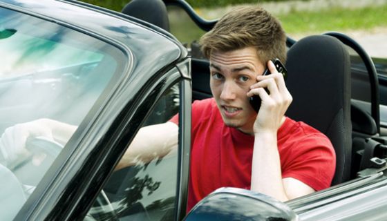 Teenager fährt Auto und telefoniert mit dem Handy.