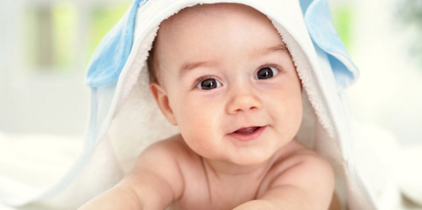 Baby auf Bauch liegend mit blauen Augen