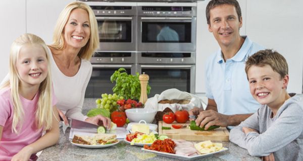 Familie sitzt am Tisch und isst Obst und Gemüse.