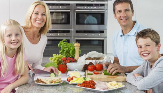 Familie sitzt am Tisch und isst Obst und Gemüse.