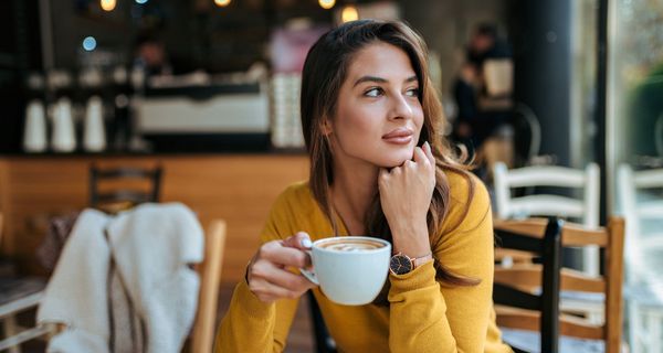 Frau mit Kaffeetasse, sitzt in einem Café.