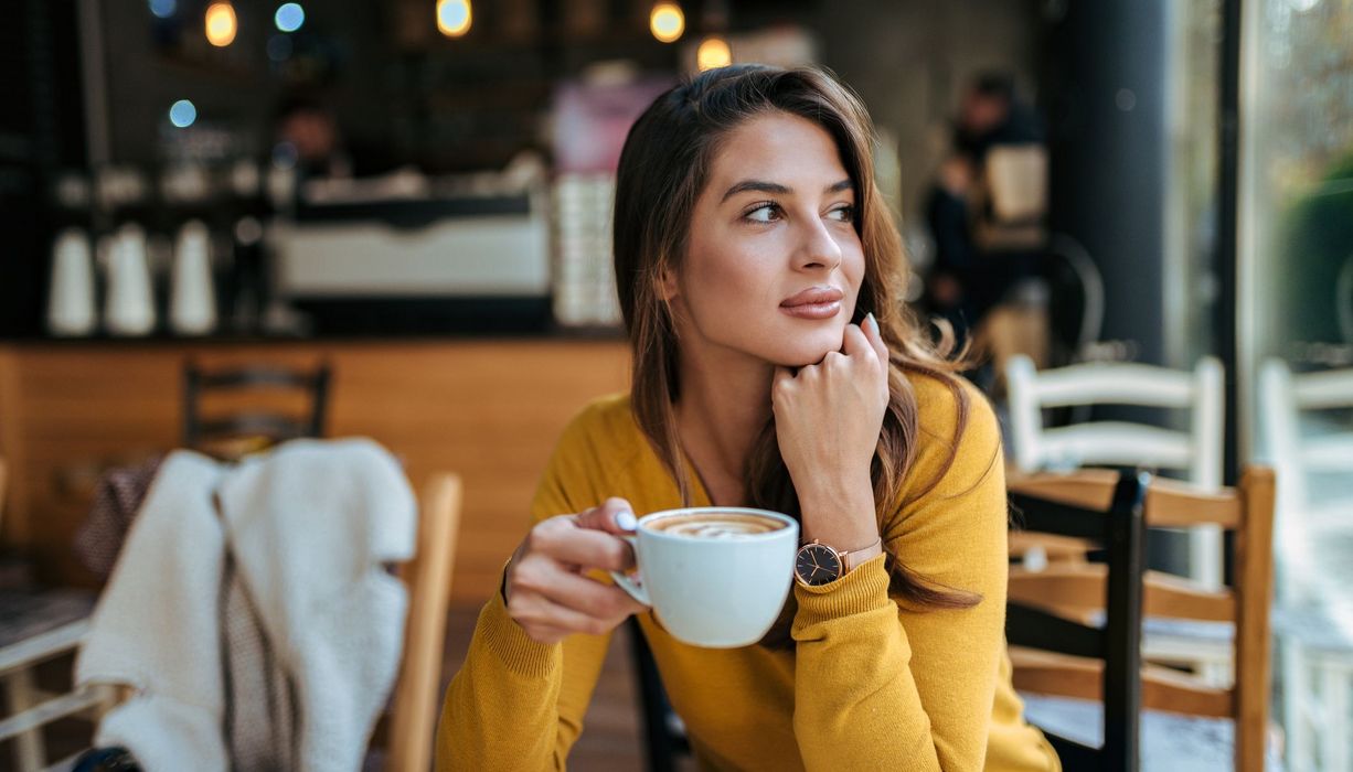 Frau mit Kaffeetasse, sitzt in einem Café.