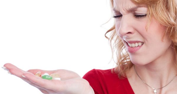 Junge Frau rümpft die Nase beim Anblick von Tabletten