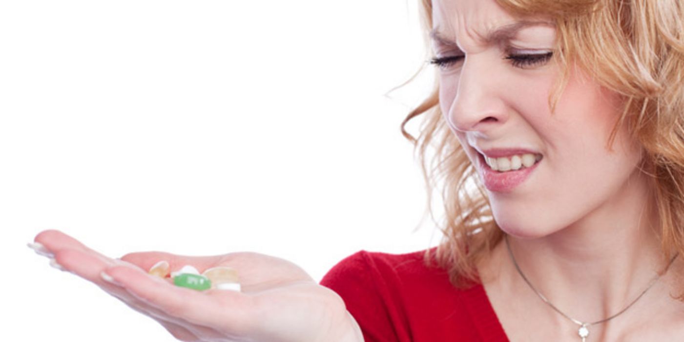 Junge Frau rümpft die Nase beim Anblick von Tabletten