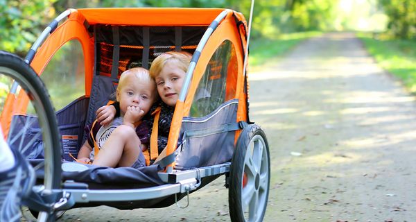 Zwei Kinder sitzen in einem Fahrradanhänger