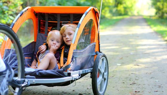 Zwei Kinder sitzen in einem Fahrradanhänger