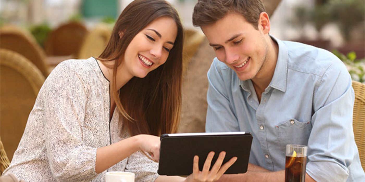 Junges, attraktives Paar im Café, schauen gemeinsam auf Tablet-PC