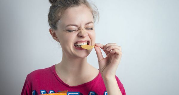 Jugendliches Mädchen, beißt in Chips.