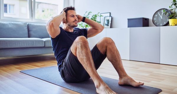 Mann, macht Sit-ups im Wohnzimmer.