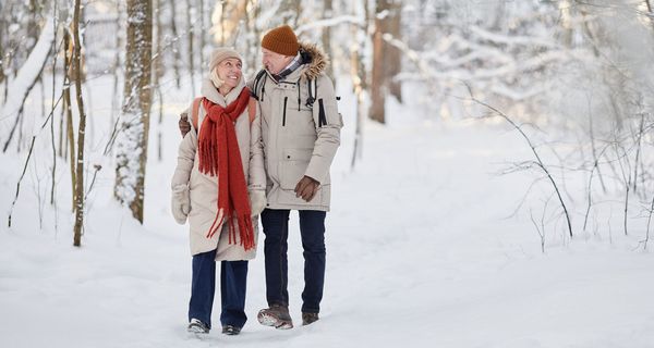 Älteres Paar macht einen Spaziergang durch einen Winterwald.