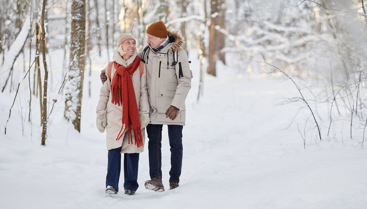 Älteres Paar macht einen Spaziergang durch einen Winterwald.