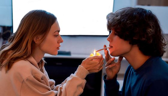 Eine Jugendliche zündet einem Jugendlichen einen Joint an.