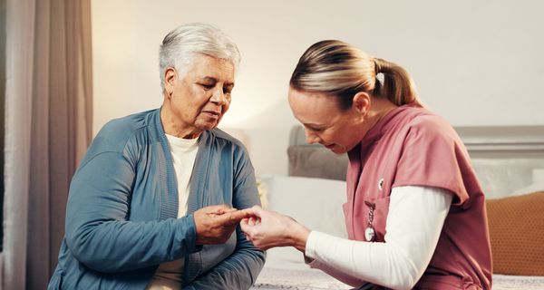 Pflegerin misst Frau den Blutzucker.