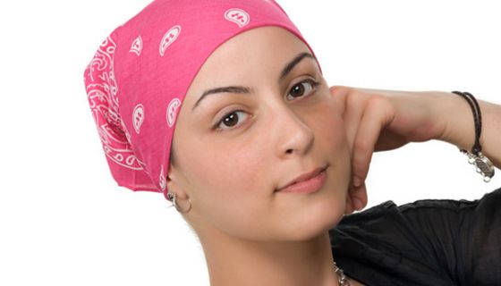 Porträtfoto: Junge Frau, dunkle Augen, rosa-weiß-gemustertes Nikkituch um den Kopf gebunden, auf einen Ellenbogen gestützt, in die Kamera schauend