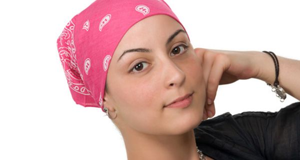 Porträtfoto: Junge Frau, dunkle Augen, rosa-weiß-gemustertes Nikkituch um den Kopf gebunden, auf einen Ellenbogen gestützt, in die Kamera schauend