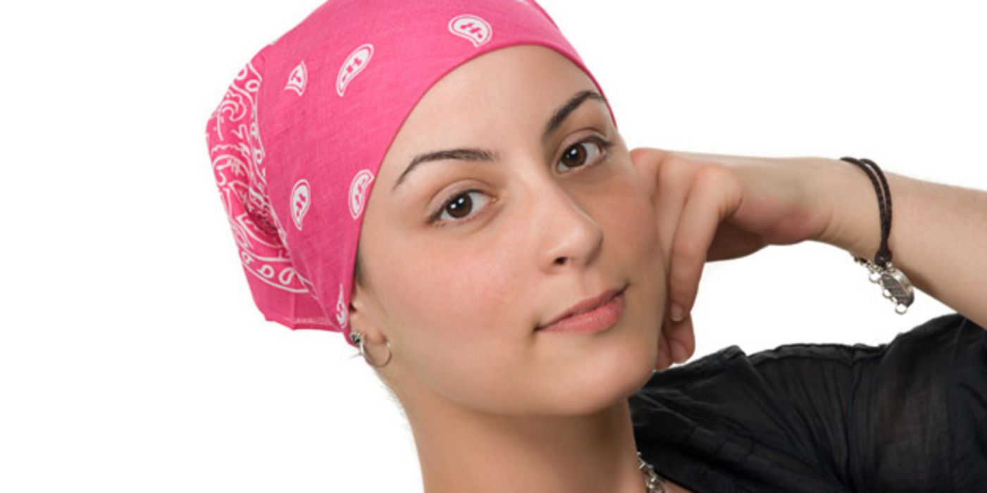 Porträtfoto: Junge Frau, dunkle Augen, rosa-weiß-gemustertes Nikkituch um den Kopf gebunden, auf einen Ellenbogen gestützt, in die Kamera schauend