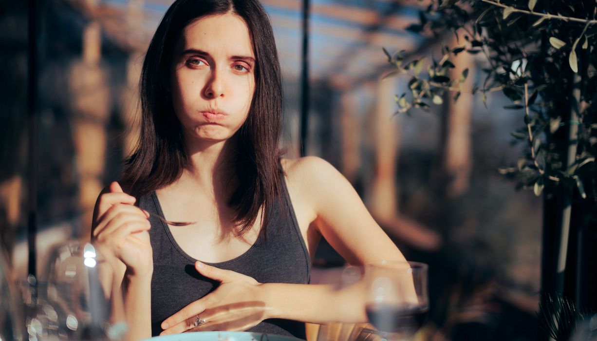 Junge Frau fühlt sich unangenehm voll nach dem Essen.